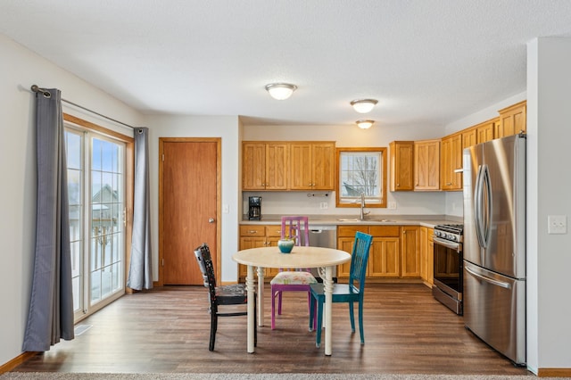 kitchen featuring appliances with stainless steel finishes, sink, a textured ceiling, and light hardwood / wood-style flooring