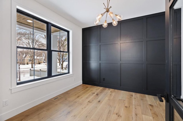 spare room with a healthy amount of sunlight, light wood-style floors, and a decorative wall