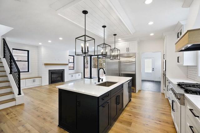 kitchen featuring a center island with sink, light countertops, hanging light fixtures, open floor plan, and white cabinets