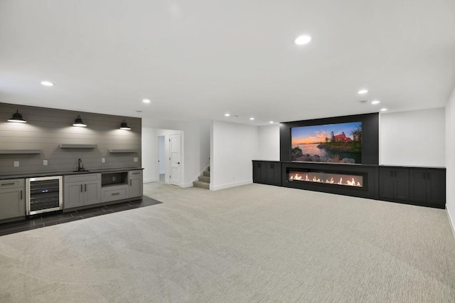 home theater room featuring light carpet, beverage cooler, a glass covered fireplace, a sink, and recessed lighting