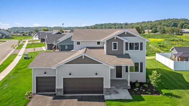 view of front of property featuring driveway, a garage, a shingled roof, a residential view, and fence