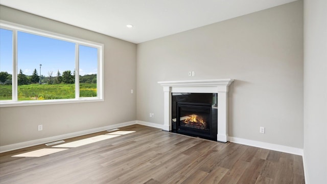 7472 170th Ave NW, Ramsey, MN 55303 - unfurnished living room featuring a fireplace with flush hearth, baseboards, visible vents, and wood finished floors