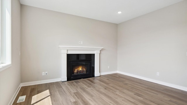 7472 170th Ave NW, Ramsey, MN 55303 - unfurnished living room with wood finished floors, a glass covered fireplace, baseboards, visible vents, and recessed lighting