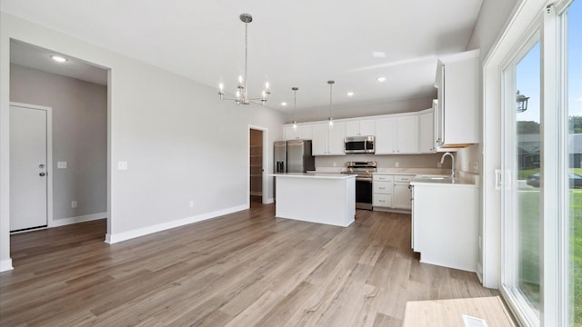 7472 170th Ave NW, Ramsey, MN 55303 - kitchen featuring light countertops, stainless steel appliances, a kitchen island, a sink, and light wood-style floors