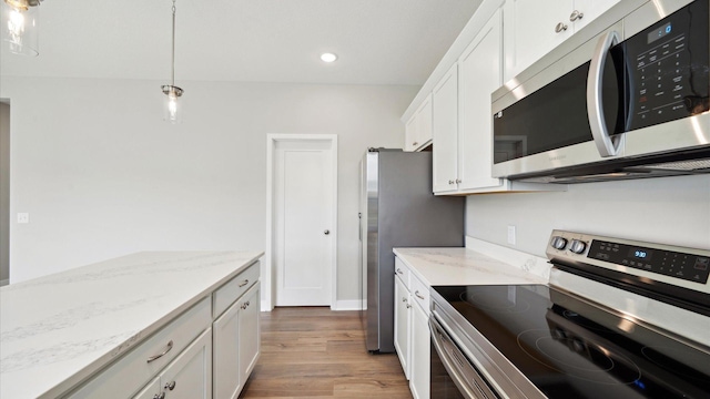 7472 170th Ave NW, Ramsey, MN 55303 - kitchen with white cabinets, light wood-style flooring, stainless steel appliances, light stone counters, and pendant lighting