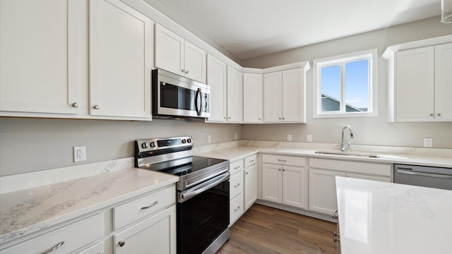 7472 170th Ave NW, Ramsey, MN 55303 - kitchen with white cabinetry, dark wood-type flooring, a sink, light stone counters, and appliances with stainless steel finishes