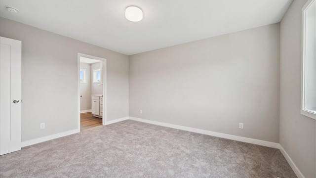 7472 170th Ave NW, Ramsey, MN 55303 - unfurnished bedroom featuring baseboards, connected bathroom, and light colored carpet