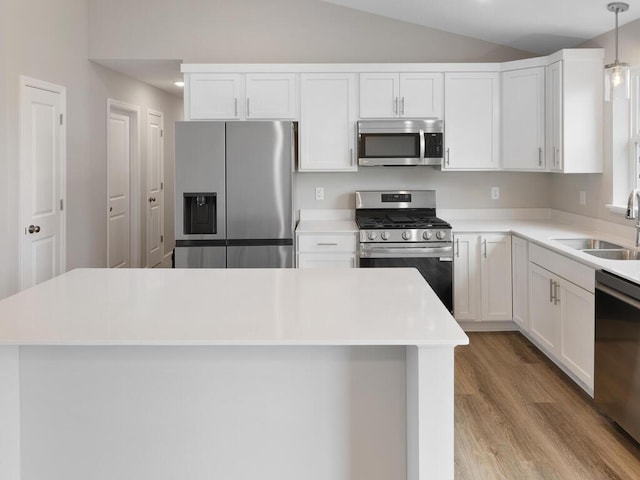 kitchen featuring lofted ceiling, sink, white cabinets, hanging light fixtures, and stainless steel appliances