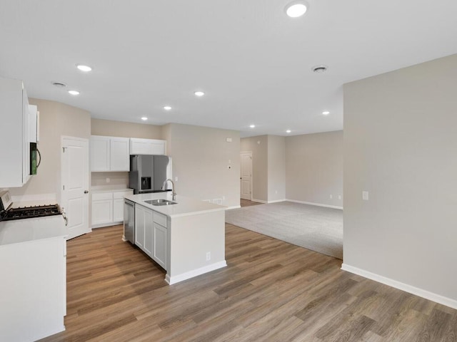 kitchen with white cabinetry, sink, a kitchen island with sink, light hardwood / wood-style floors, and stainless steel appliances