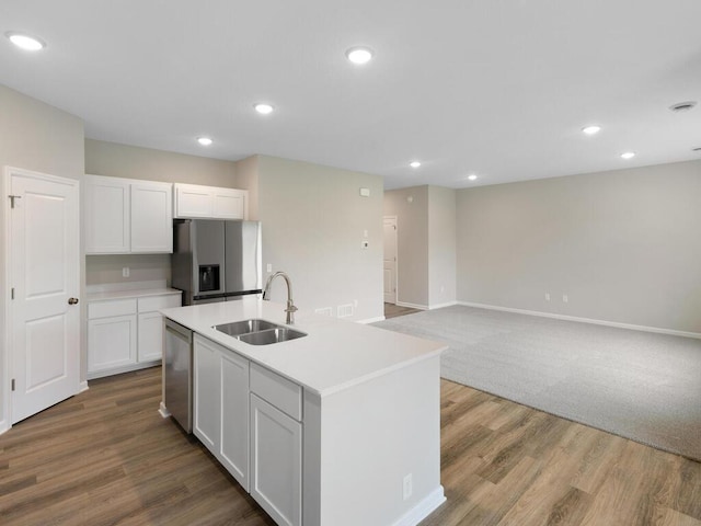 kitchen with sink, white cabinetry, wood-type flooring, a center island with sink, and appliances with stainless steel finishes