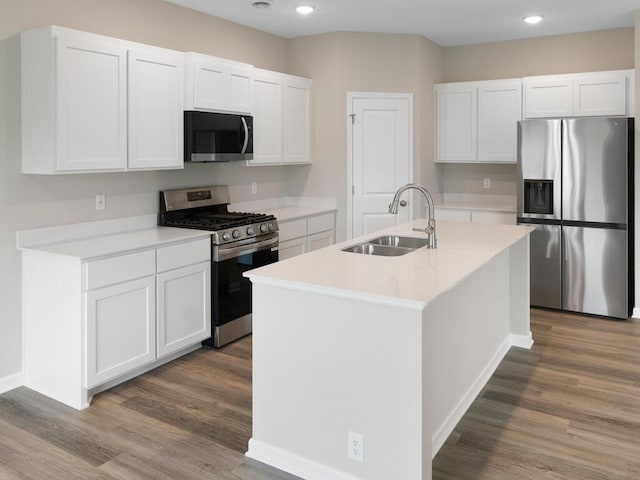 kitchen with sink, hardwood / wood-style flooring, white cabinetry, stainless steel appliances, and an island with sink