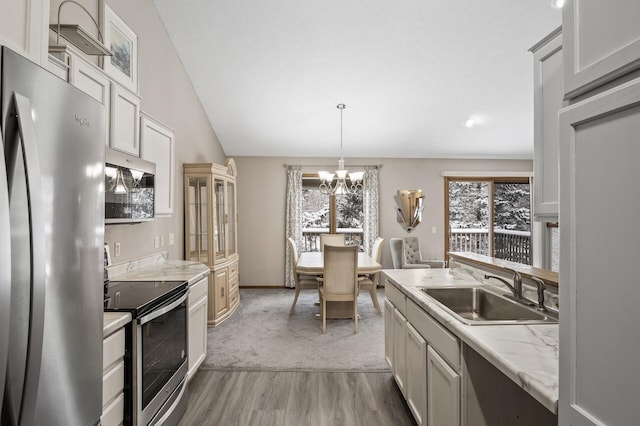 kitchen featuring sink, white cabinetry, vaulted ceiling, appliances with stainless steel finishes, and pendant lighting