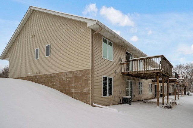 snow covered property with central AC unit and a deck