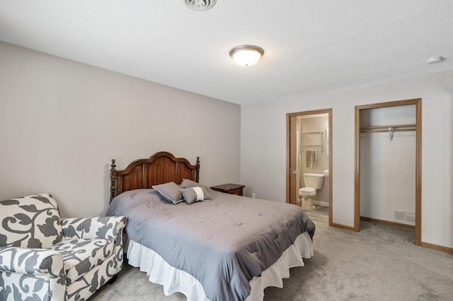 bedroom featuring ensuite bath, light colored carpet, a closet, and a textured ceiling