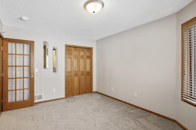 unfurnished bedroom featuring a closet, a textured ceiling, and carpet flooring