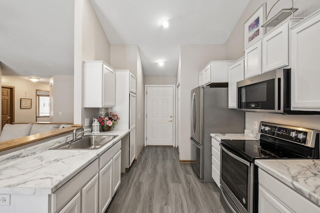 kitchen with sink, appliances with stainless steel finishes, light stone counters, white cabinets, and light wood-type flooring