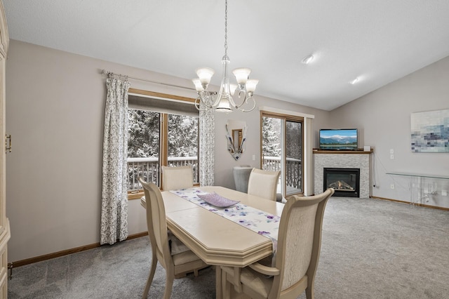 dining space featuring a tile fireplace, lofted ceiling, light colored carpet, and a chandelier