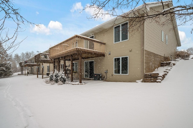 snow covered house with a wooden deck and central AC