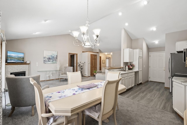 dining space featuring lofted ceiling, sink, hardwood / wood-style floors, and an inviting chandelier