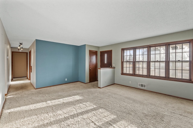 unfurnished room featuring baseboards, visible vents, carpet floors, and a textured ceiling