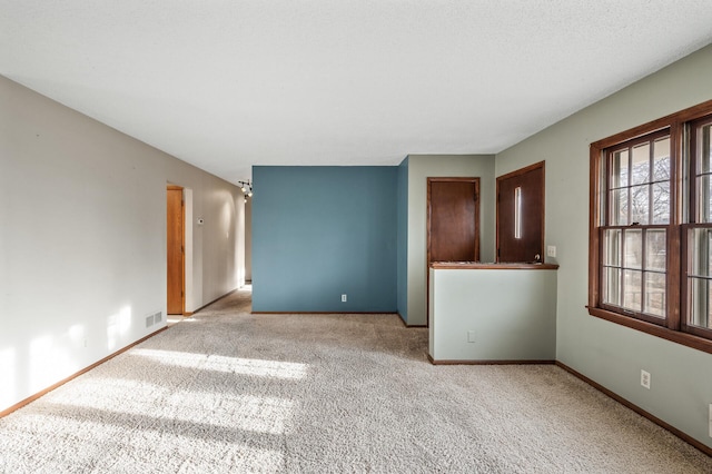 unfurnished room with visible vents, light colored carpet, and baseboards