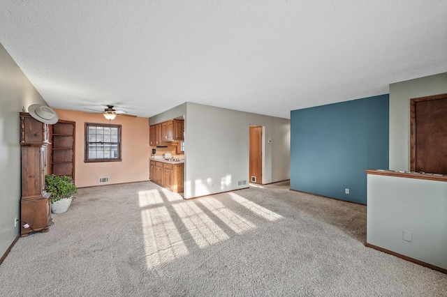 unfurnished living room featuring visible vents, light colored carpet, baseboards, and a textured ceiling