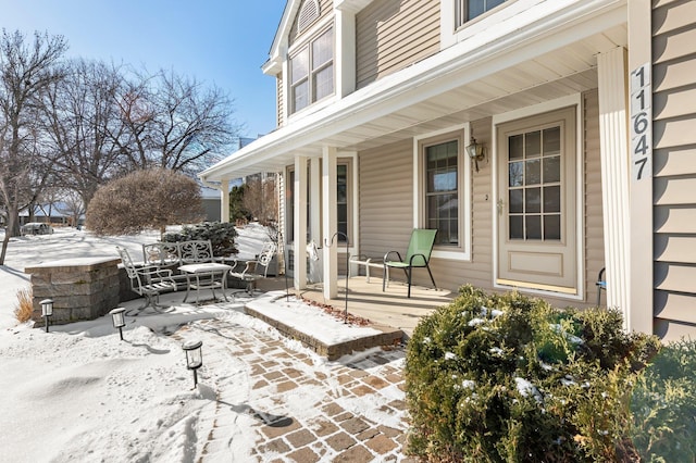 snow covered patio featuring covered porch