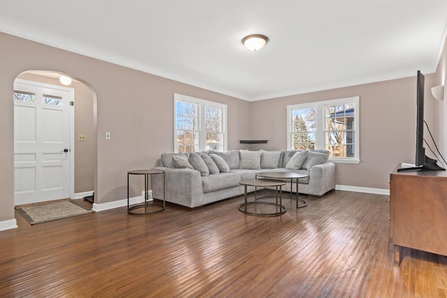 living room with ornamental molding, arched walkways, wood-type flooring, and baseboards