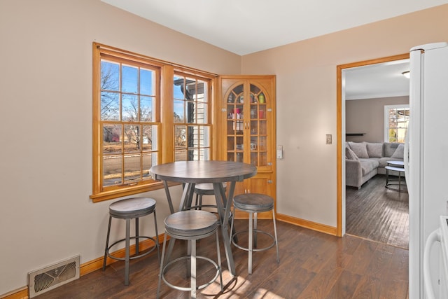 dining area featuring baseboards, visible vents, and dark wood-type flooring