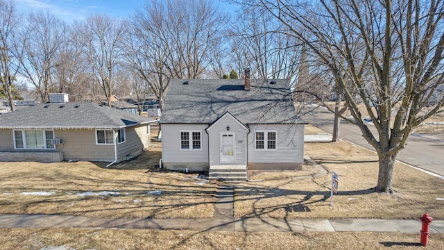 view of front of property featuring a shingled roof, cooling unit, and a chimney