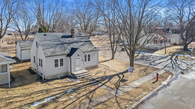 view of side of home with a shingled roof and a chimney