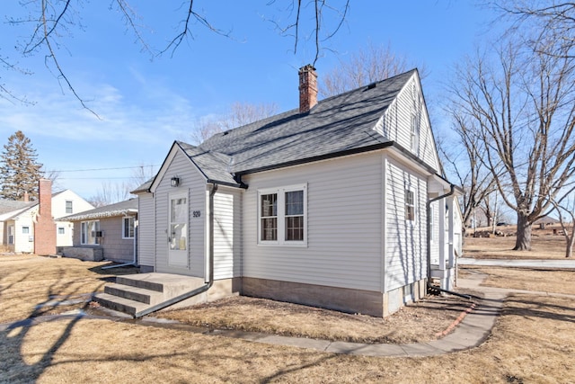 view of front of property with a shingled roof and a chimney