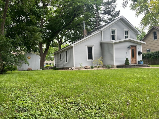 view of front of property with a front yard and a storage shed