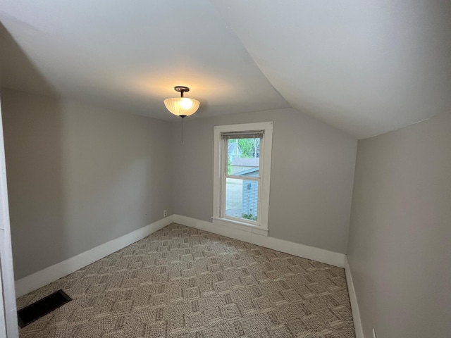 bonus room with lofted ceiling and light carpet