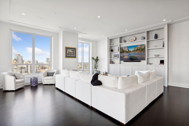 living room with plenty of natural light, dark hardwood / wood-style floors, and built in shelves