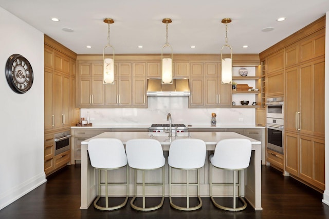 kitchen featuring hanging light fixtures, a kitchen island with sink, dark hardwood / wood-style flooring, and wall chimney exhaust hood