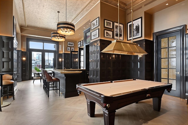 rec room with a towering ceiling, bar area, pool table, and light parquet floors