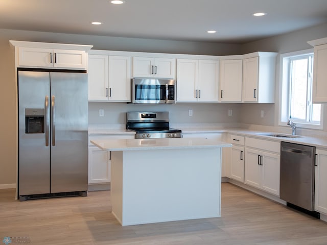 kitchen featuring white cabinetry, sink, a center island, stainless steel appliances, and light hardwood / wood-style flooring