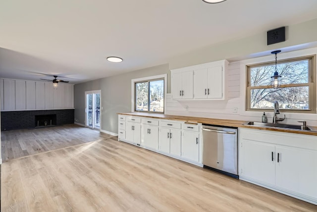 kitchen with sink, wooden counters, white cabinets, decorative light fixtures, and stainless steel dishwasher