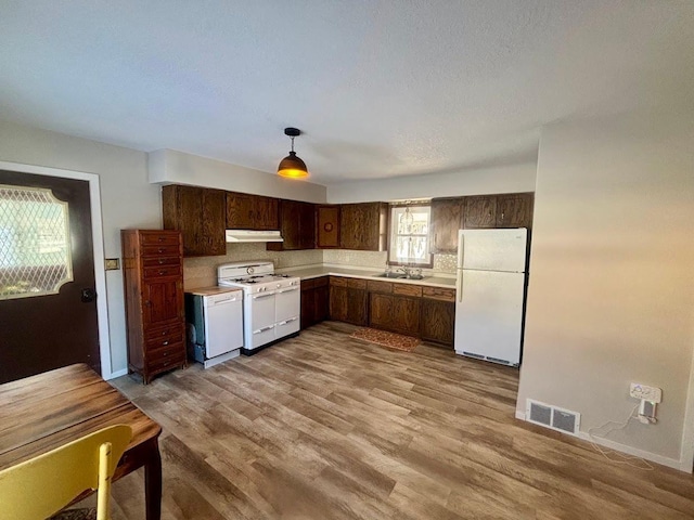 kitchen featuring white appliances, visible vents, light countertops, dark brown cabinets, and under cabinet range hood