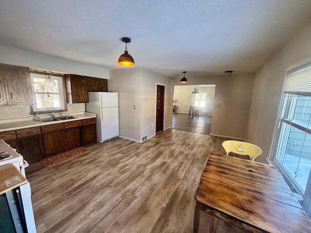 kitchen with white appliances, plenty of natural light, wood finished floors, light countertops, and a sink