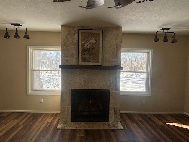 unfurnished living room featuring a healthy amount of sunlight, baseboards, dark wood-style flooring, and a textured ceiling