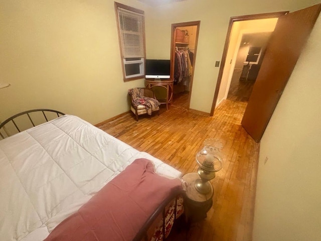 bedroom with a walk in closet, a closet, and light wood-style flooring