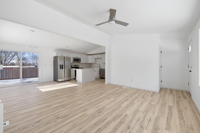 unfurnished living room with ceiling fan, lofted ceiling, sink, and light wood-type flooring