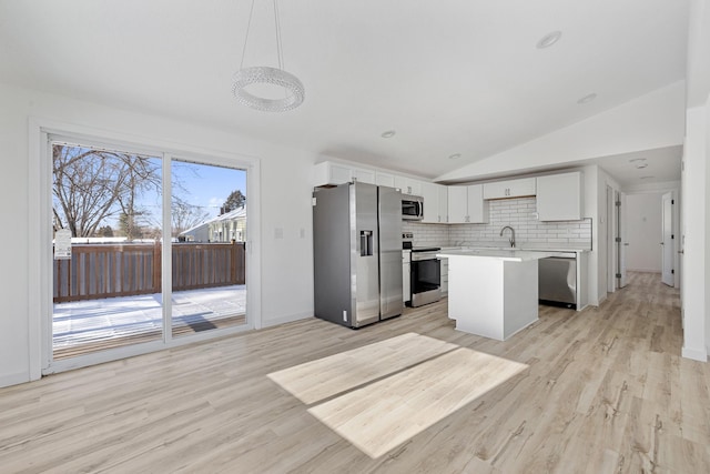 kitchen featuring white cabinetry, decorative light fixtures, vaulted ceiling, a kitchen island, and stainless steel appliances