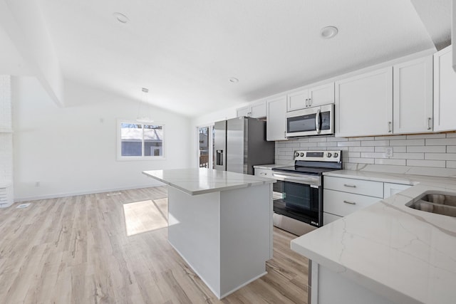 kitchen with white cabinetry, hanging light fixtures, stainless steel appliances, and a kitchen island