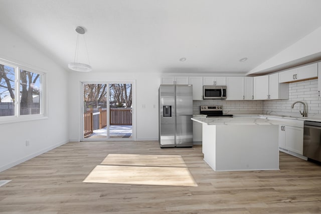 kitchen with vaulted ceiling, decorative light fixtures, a center island, stainless steel appliances, and light stone countertops