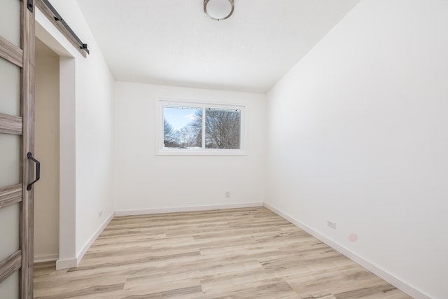 unfurnished room featuring a barn door and light wood-type flooring