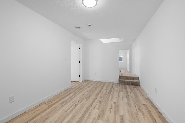 interior space featuring a textured ceiling, light hardwood / wood-style floors, and a skylight