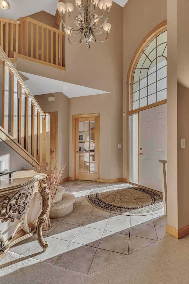 tiled foyer featuring a healthy amount of sunlight, a chandelier, and a high ceiling